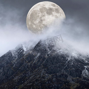 月球山脉摄影照片_山脉上方的超级月亮美丽的数字合成图像为戏剧性的风景图像赋予了非常超现实的奇幻外观