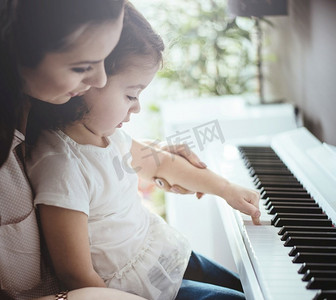 妈妈教她的小女儿弹钢琴