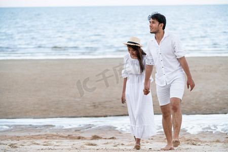 蜜月旅行度假期间，幸福的年轻夫妇在海滩上漫步。幸福的年轻夫妇蜜月漫步在海滩上。