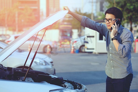 一个人在旅途中开着一辆坏车，他正在打电话给一个机修工。