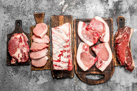 不同种类的生肉放在木板上。在乡村背景下。不同种类的生肉放在木板上。