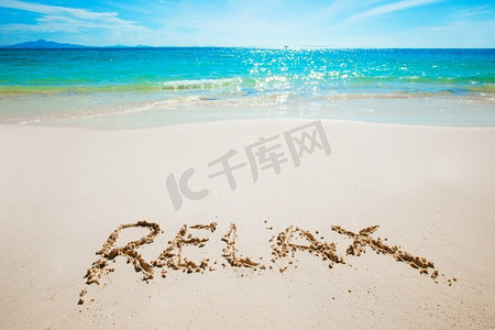 热带海滩上的Realax文字书写。Realax在海滩上写字