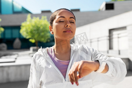 技术，运动和健身概念—年轻女性与智能手表呼吸户外。年轻女子与智能手表呼吸户外