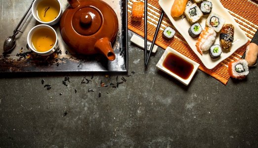 日本料理。面包卷，寿司和热茶。在石桌上。日本料理。面包卷，寿司和热茶。