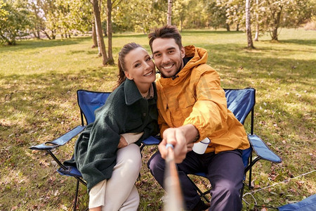 露营，旅游和旅行概念-幸福的情侣在帐篷营地喝茶和自拍。一对夫妇在帐篷营地喝茶自拍