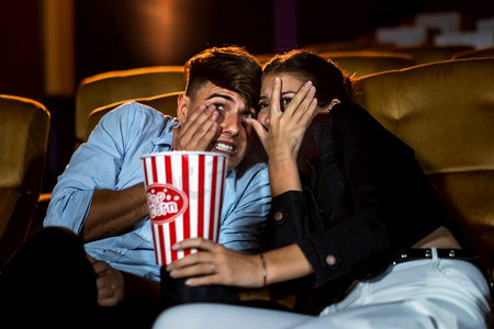 一对情侣看电影震惊和眼睛关闭在电影院电影院。