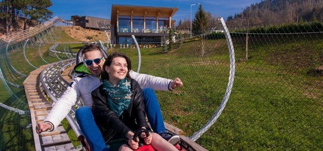 兴奋的年轻夫妇驾驶高山过山车，同时享受美丽的晴天在自然