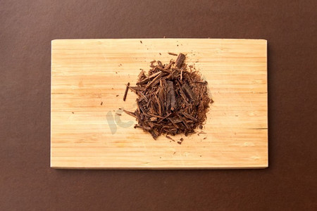 糖果、糖果和烹饪概念-棕色背景下木板上的巧克力片。木板上的巧克力片