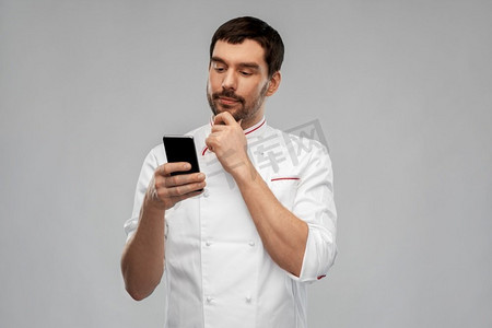 烹饪，烹饪和人的概念思考男性厨师有智能手机在灰色背景。思考男性厨师与智能手机