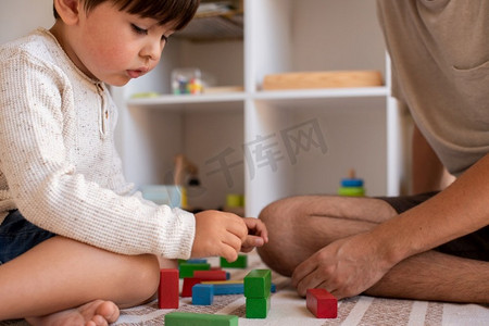 小孩子和他的父亲在家里玩木积木。在家上学。呆在家里家庭时间