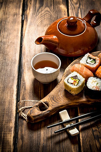 山葵摄影照片_寿司和面包卷配花草茶。在一张木桌上。寿司和面包卷配花草茶。