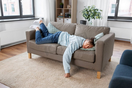 人，无聊和抑郁的概念—懒惰的年轻人睡在家里的沙发上。年轻人睡在沙发上在家里