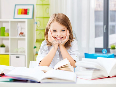 教育和学校概念—微笑的学生女孩与书籍学习在家庭房间背景。微笑的学生女孩与书籍学习在家里