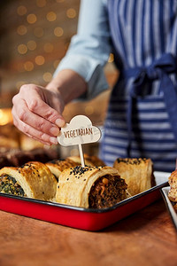 面包店的销售助理将素食免费标签放入新鲜烘焙的咸味卷