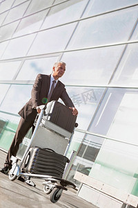 成熟商人在机场推着行李车的肖像