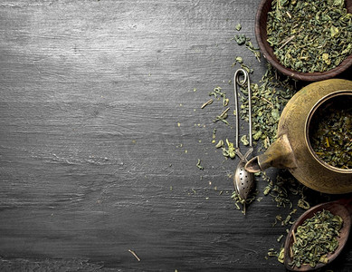 陈旧茶壶中的芳香绿茶。在黑色黑板上。陈旧茶壶中的芳香绿茶。