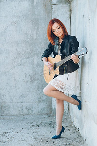 音乐家年轻女孩与红头发与原声吉他