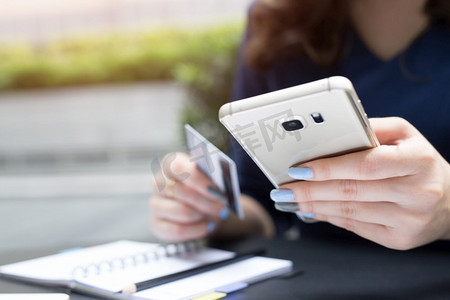 一名女子使用信用卡通过手机在网上购物。