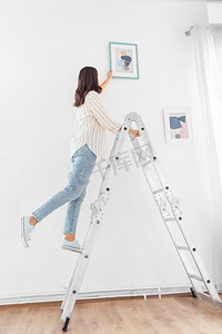 家庭改善、装饰和人概念—在梯子装饰家与艺术的愉快的微笑的妇女在梯子装饰家与艺术的妇女
