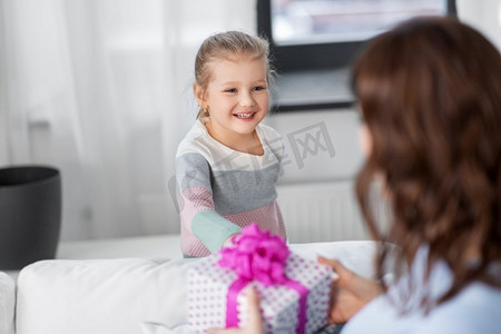 人，家庭和假期概念—快乐的小女儿在家里给她的母亲礼物。快乐的女儿给母亲在家里的礼物