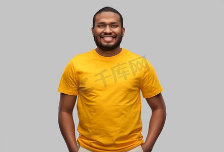 人们概念—微笑的年轻非洲裔美国人在灰色背景的黄色t恤。微笑的非洲裔美国人在黄色T恤