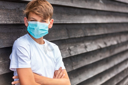 在冠状病毒COVID—19病毒大流行期间，男孩青少年未成年男孩戴着面罩在外面
