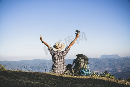 传奇大背包摄影照片_从山顶来的游客阳光。男子穿着大背包反对阳光