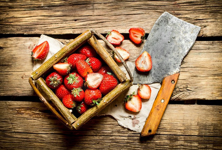 草莓放在带斧头的篮子里。在一张木桌上..篮子里的草莓