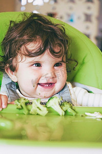 互补摄影照片_婴儿吃食物在她的绿色高脚椅