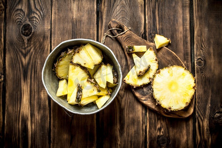 把菠萝片放在锅里。在一张木桌上。把菠萝片放在锅里。