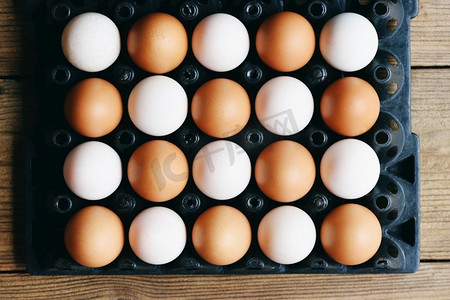 新鲜的鸡蛋和鸭蛋在鸡蛋盒在木桌子背景，光和阴影概念
