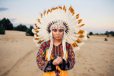 纳瓦霍人摄影照片_年轻的美国印第安人的脸，切诺基人，纳瓦霍人。由野鸟的羽毛制成的头饰。美国印第安人的脸，切诺基人，纳瓦霍人