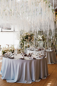 餐厅宴会厅的新婚夫妇主席团用蜡烛和绿色植物装饰，紫藤从天花板上垂下来