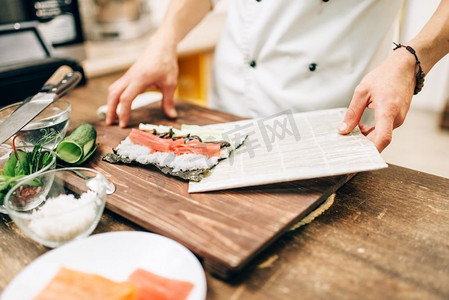 男厨师做寿司在木桌，亚洲厨房准备过程。传统日本料理、海鲜