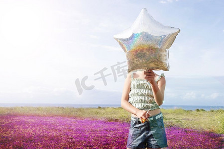 遮脸摄影照片_田野中用星气球遮脸的少女肖像