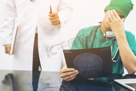 面部x光摄影照片_医疗失败概念—外科医生用手（面部手掌）遮住他的脸，表示失望，而在办公桌上拿着X光胶片。