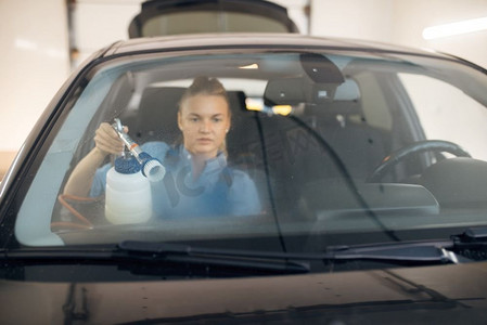 女洗衣工清洁汽车内部，透过挡风玻璃查看，洗车。妇女洗车，洗车站，洗车业务
