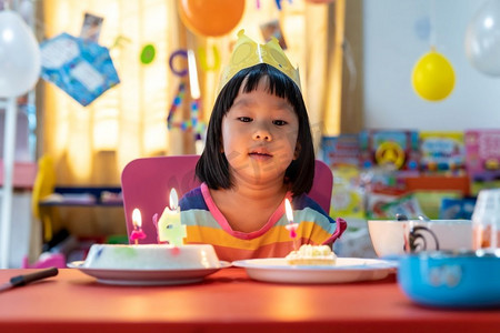 家人聚会摄影照片_亚洲女孩带着生日蛋糕与家人单独庆祝，因为城市封锁而新冠肺炎大流行。摄氏检疫和检疫概念。