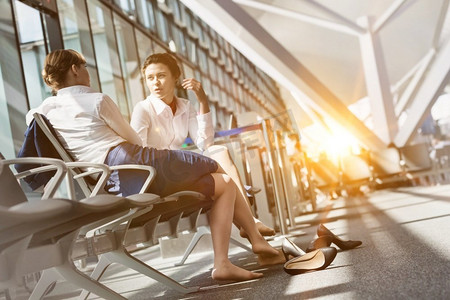 年轻的有吸引力的机场工作人员坐着，而在机场休息期间谈话