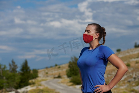 疫情后摄影照片_运动型妇女，带防护面罩，跑步后休息和放松