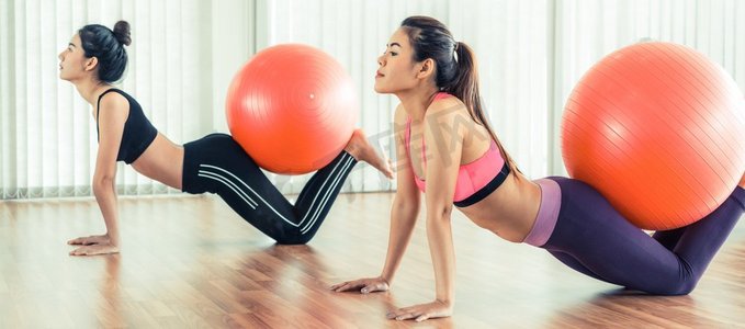 健身球摄影照片_女性在健身房或瑜伽课上用健身球做运动。健康的生活方式理念。