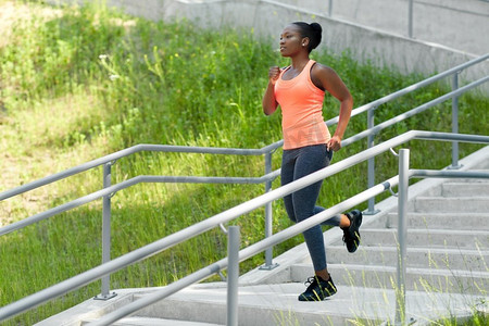 轻松上下楼摄影照片_健身，运动和健康的生活方式概念—年轻的非洲裔美国妇女跑下楼。年轻的非洲裔美国妇女跑下楼