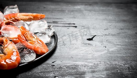 盘子里放着冰的虾。在黑色黑板上。盘子里放着冰的虾。