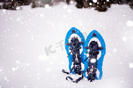 冬天徒步旅行在山的蓝色雪鞋在新鲜的显示与雪花在他们周围在下雪的冬天