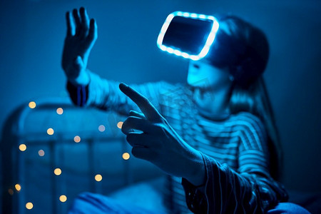 十几岁的女孩玩视频游戏在家卧室穿着虚拟现实耳机在晚上
