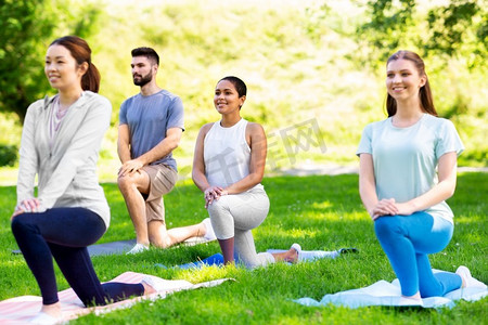 健身、运动和健康生活方式的概念-一群快乐的人在夏季公园做瑜伽。一群人在夏季公园做瑜伽