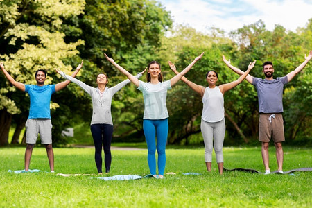 健身，运动和健康的生活方式概念—一群快乐的人在夏季公园做瑜伽。一群人在夏季公园做瑜伽