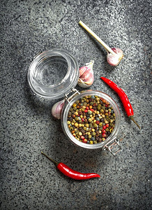 玻璃罐里的胡椒和大蒜。在一个乡村的背景下。玻璃罐里的胡椒和大蒜。
