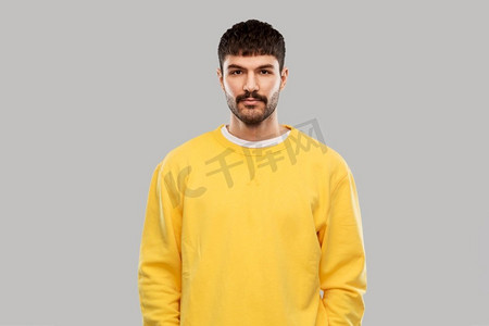 人的概念—年轻人在灰色背景黄色运动衫。穿着黄色运动衫的年轻人