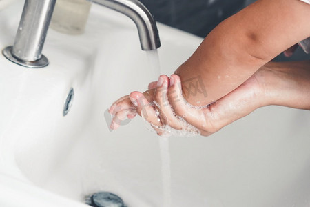 预防新型状病毒摄影照片_母亲洗手以预防新型冠状病毒病2019或COVID—19。人们在洗手池洗手以清除病毒感染。